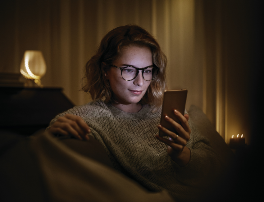 Femme regardant son téléphone avec des lunettes bénéficiant du traitement Crizal Prevencia par Essilor