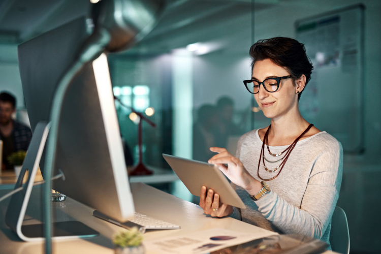 Fatigue oculaire : jeune femme portant des lunettes au bureau et adoptant la bonne posture de travail, face à son écran d'ordinateur.